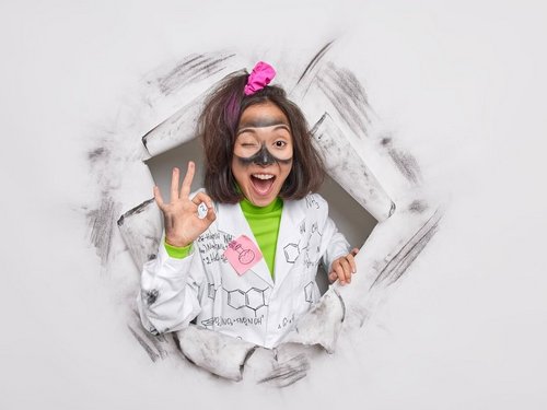 A female researcher makes a gesture to confirm that the experiment was successful and poses through a hole in the paper.