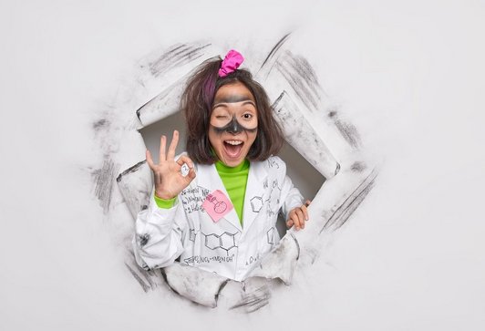 A female researcher makes a gesture to confirm that the experiment was successful and poses through a hole in the paper.